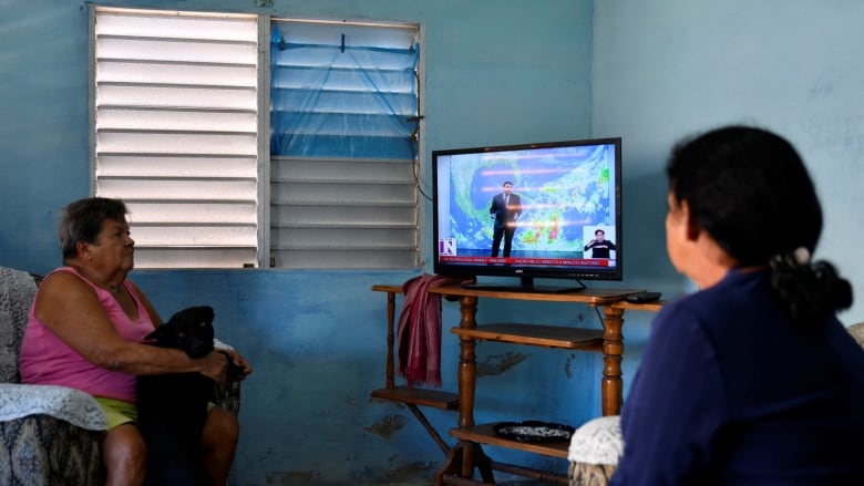 Ilda Gallardo and her daughter Marley Millian watch a local TV news program as Tropical Storm Rafael approaches, in Playa Baracoa, Cuba, November 4, 2024.