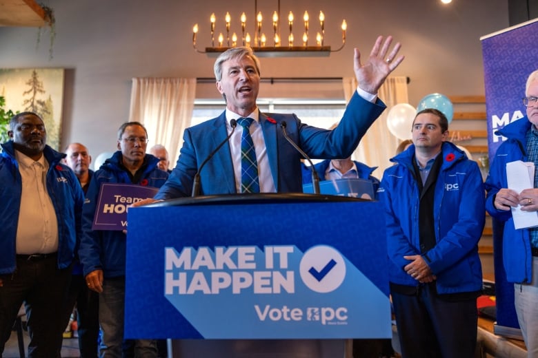 A man stands behind a podium with his arm up 