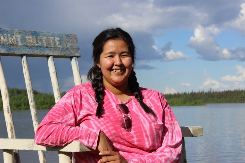 A woman sitting on a chair smiles.