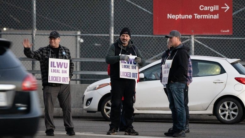 A group of workers hold sandwich boards reading 'ILWU Local 514 Locked Out'.