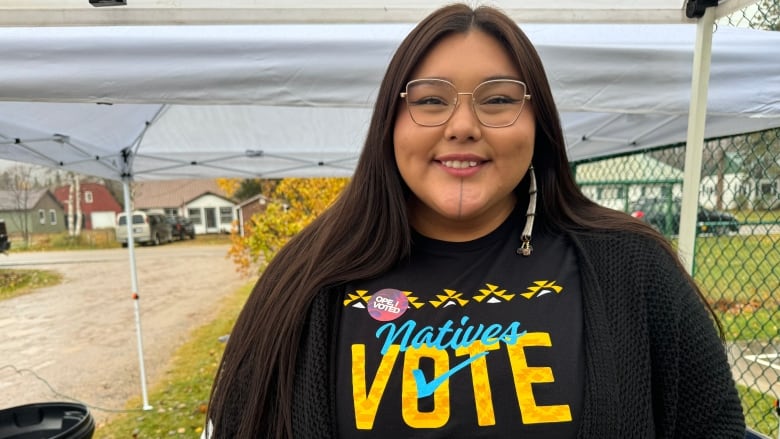 A woman wearing a shirt that reads Natives Vote smiles for the camera