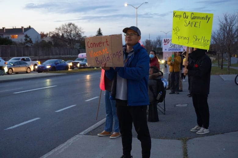 A man holding a protest sign next to a road.