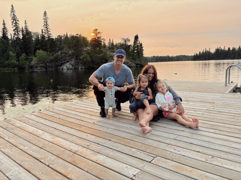 A husband and wife and three young children are seen on a dock, under a setting sun