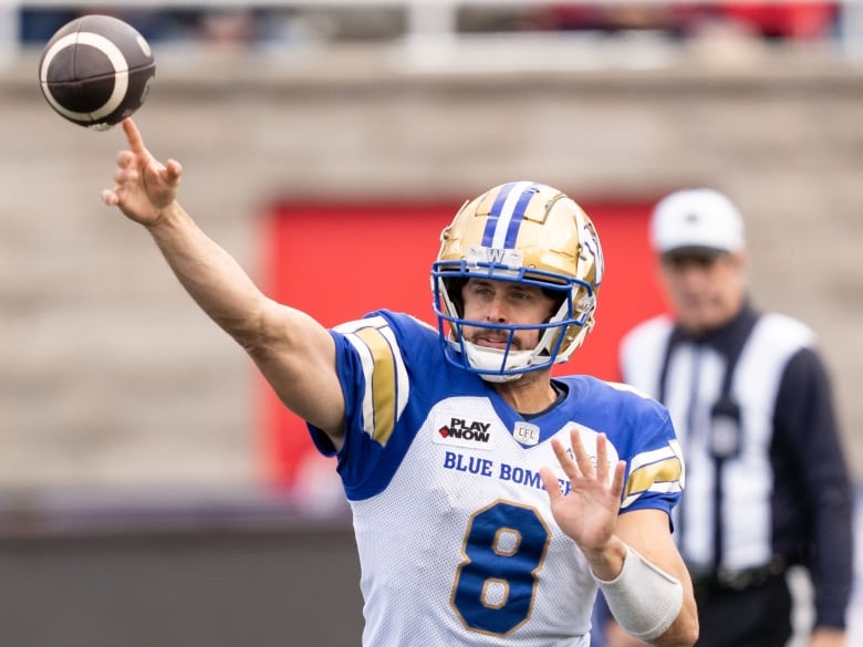 A football quarterback in blue, gold and white throws a ball