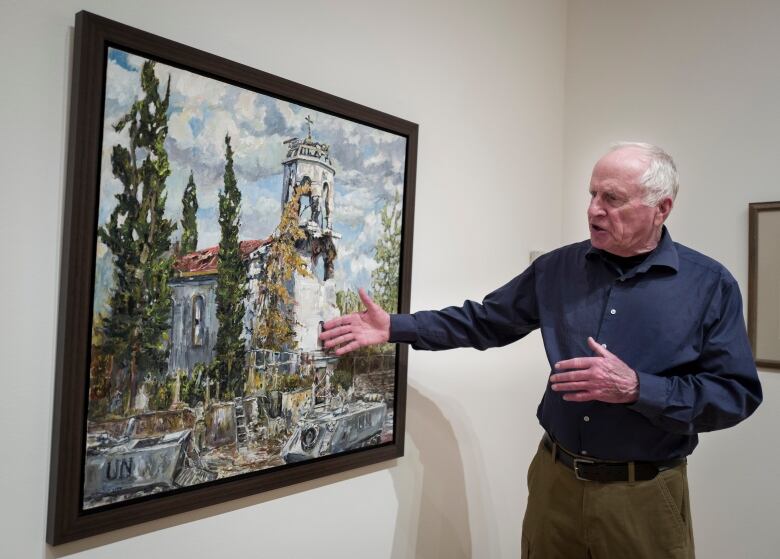 A man gestures at a painting.