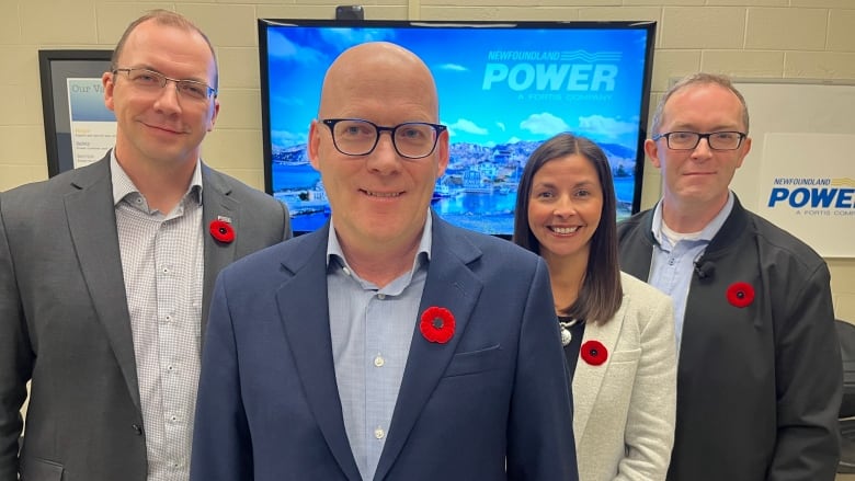 four well-dressed executives pose together for a photo