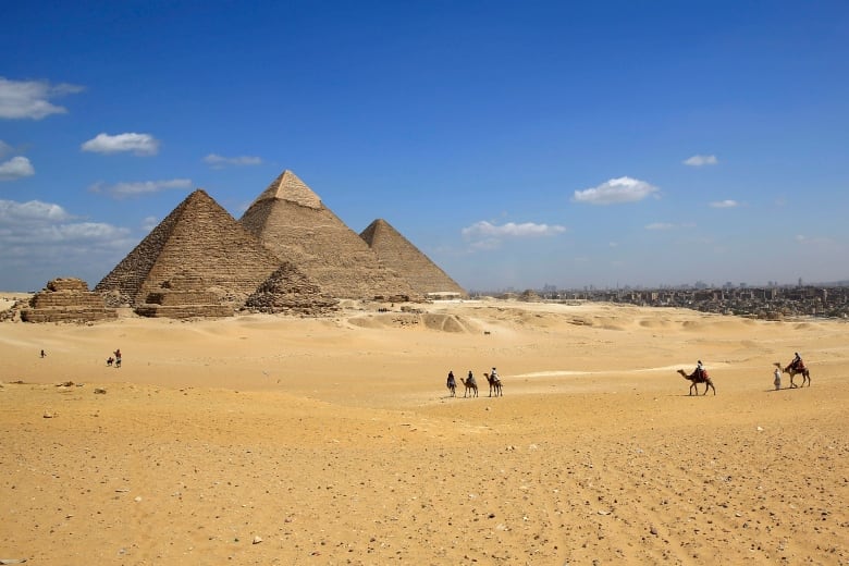 tourists ride camels at the historical site of the Giza Pyramids in Giza