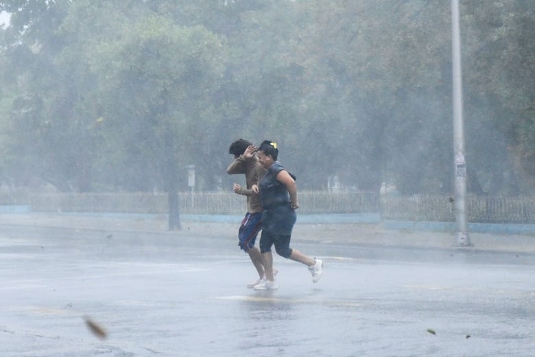 People are seen running on the street as Hurricane Rafael passes by Havana, Cuba.