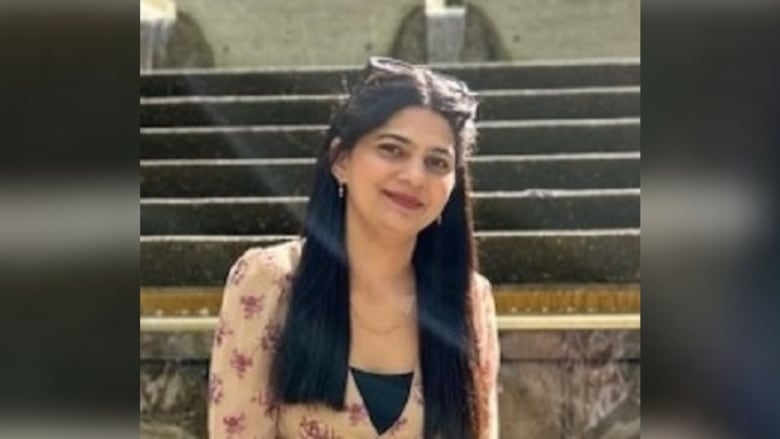 An Indian woman smiles while wearing a beige top.