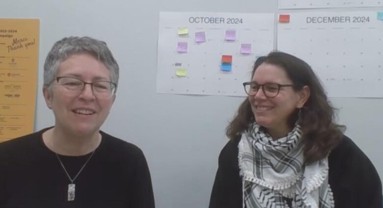 Two women sitting in an office, both smiling.