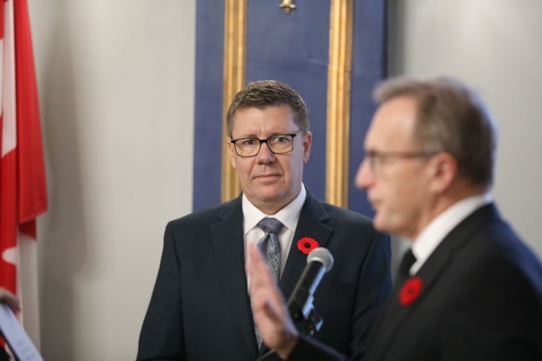 Saskatchewan Premier Scott Moe looks on as MLA Jim Reiter is sworn in during a ceremony.