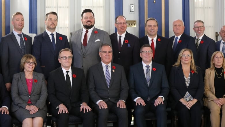 A group of men and women wearing formal clothing pose for a photo.