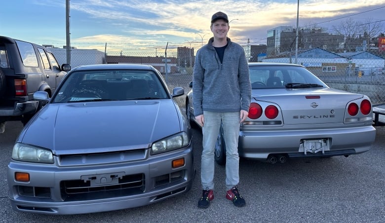 A man stands beside two Japanese-made vehicles