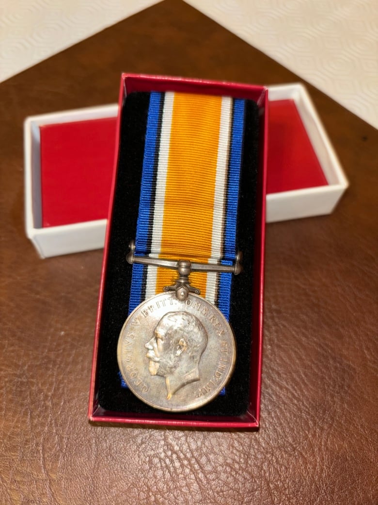 A medal with King George IV's face on it. The medal has a ribbon attached and it sits in a small box. 