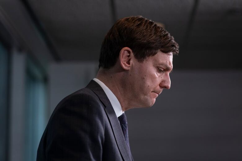 A profile shot of a man in suit looking down. 