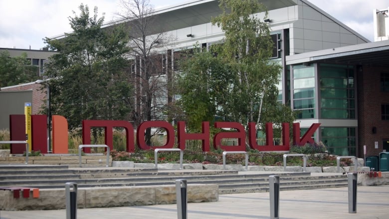 A sign in front of a modern glass building reads 