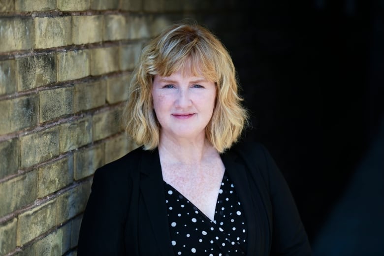 Woman standing in front of a brick wall.