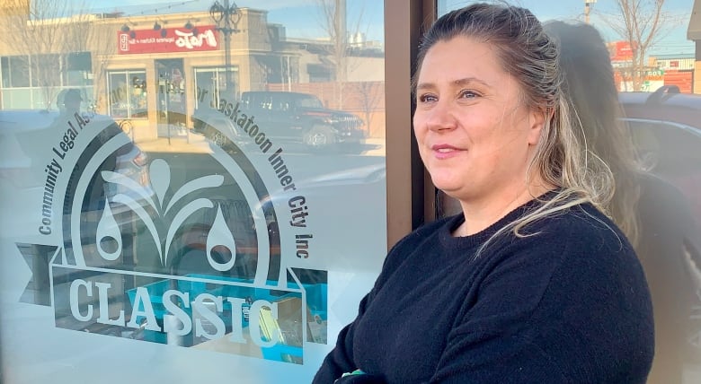 A woman in a black sweater stands in front of an office window.