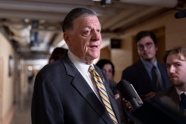 man in suit speaks to reporters