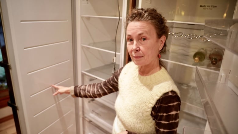 A woman holds the door open on her fridge.