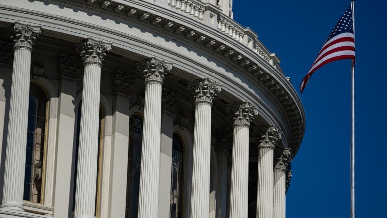 An exterior view shows part of the exterior of the U.S. Capitol building under a blue sky. 