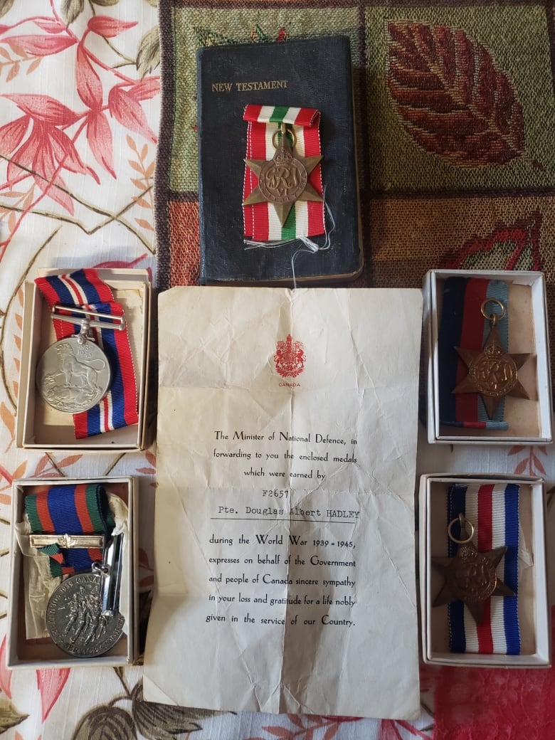 Five medals are displayed along with an official letter and a small Bible.