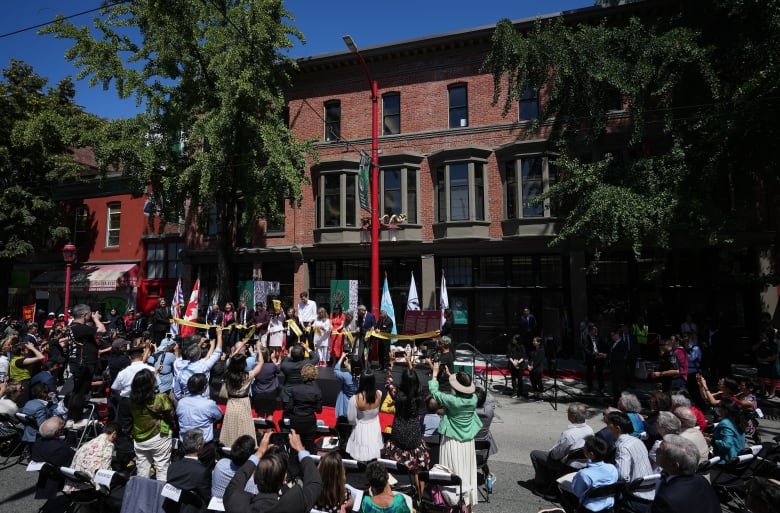 A few dozen people gather around an old building.