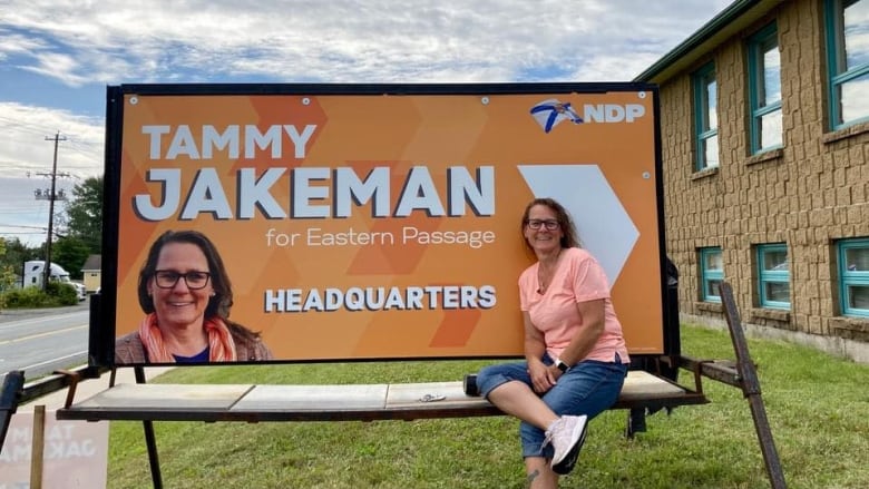 a woman sits on the ledge in fornt of a large sign that says Tammy Jakeman for Eastern Page. 