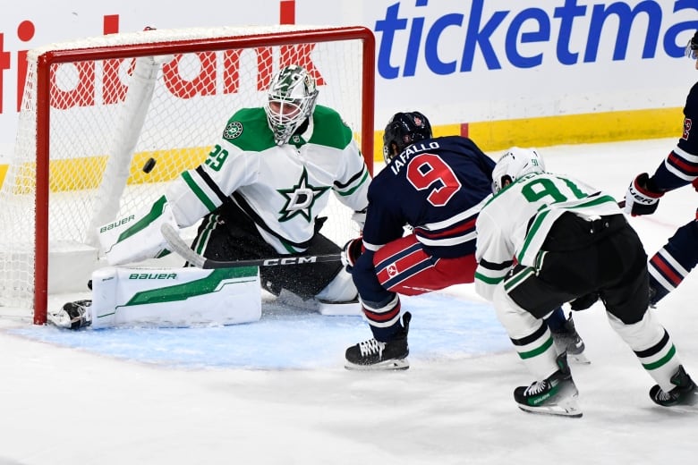 Hockey player and goalie facing each other. puck is mid-air, going towards the net.