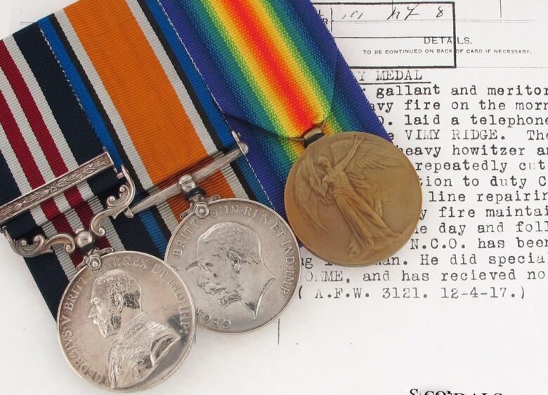 Three military medals are seen on top of a typed document.