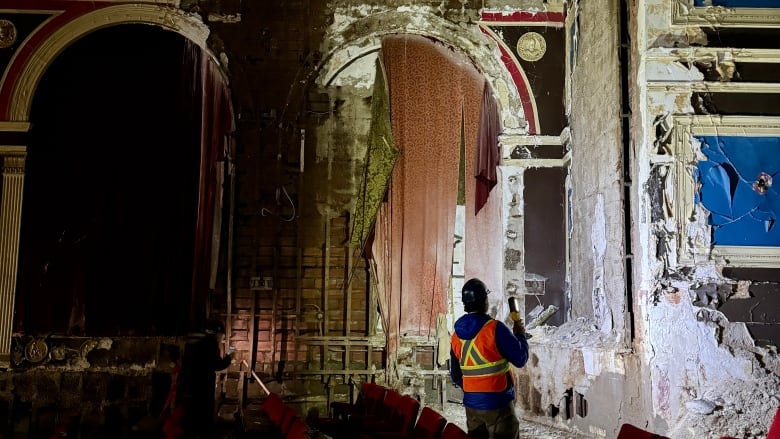 man stands in theatre that's significantly damaged