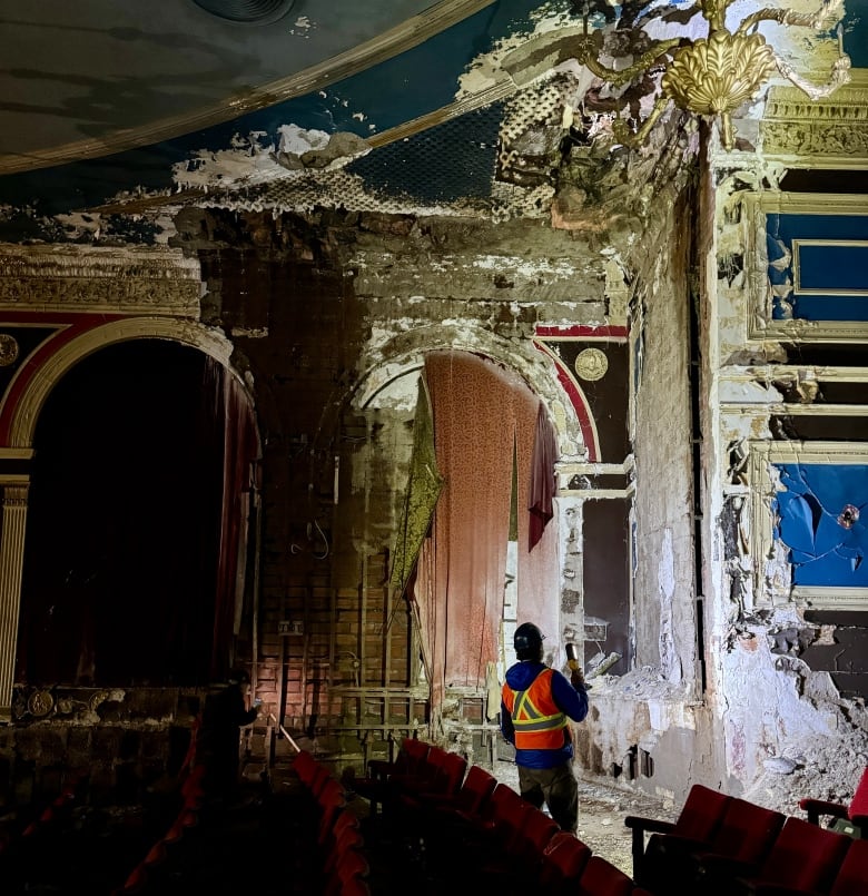 man stands in theatre that's significantly damaged