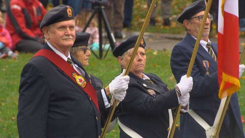 Four people in uniform watching the Remembrance Day Ceremony. 