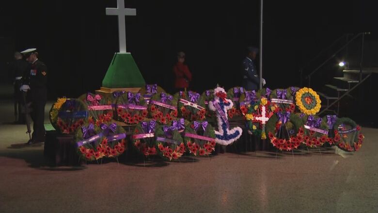 Wreaths are pictured on a table, with a cross and Canadian flag nearby.