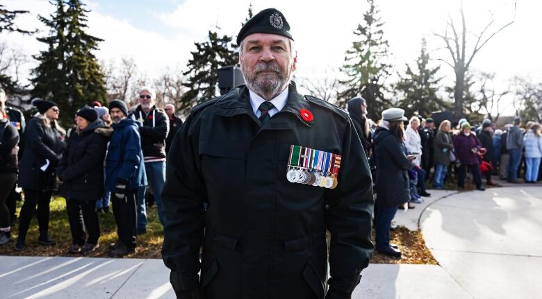 A man in a black jacket, with medals pinned to it, looks forward.