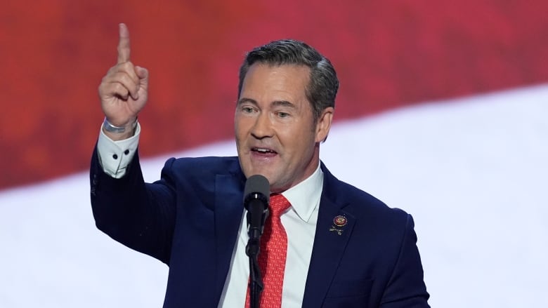 Man points up while speaking on podium