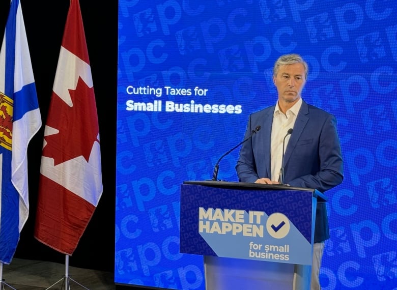 A man in a suit stands in front of a podium. 