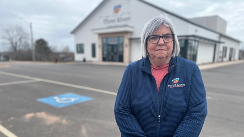 Woman in blue sweater standing outside building.