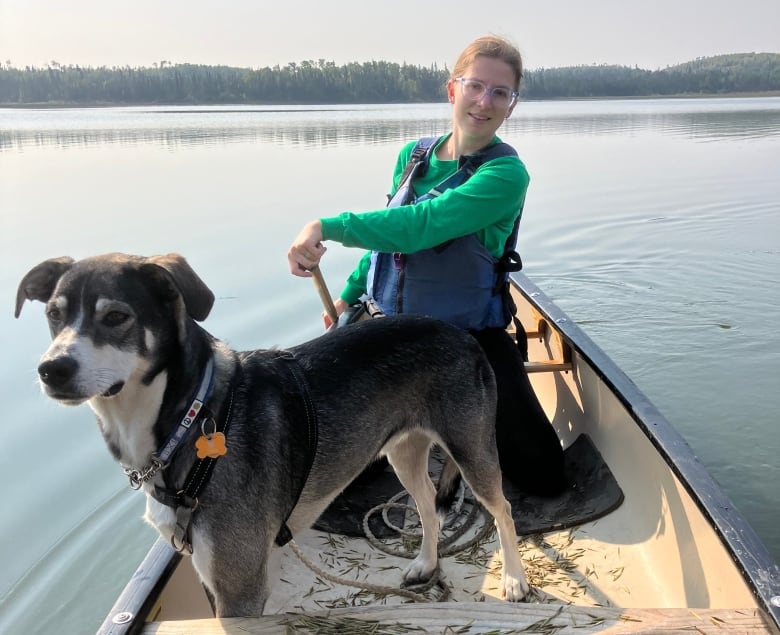 A woman is in a canoe with a dog.