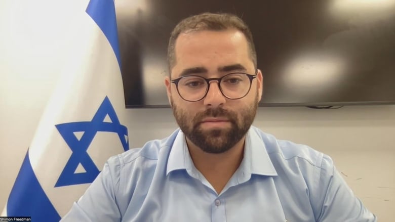 A man sits in front of an Israeli flag.