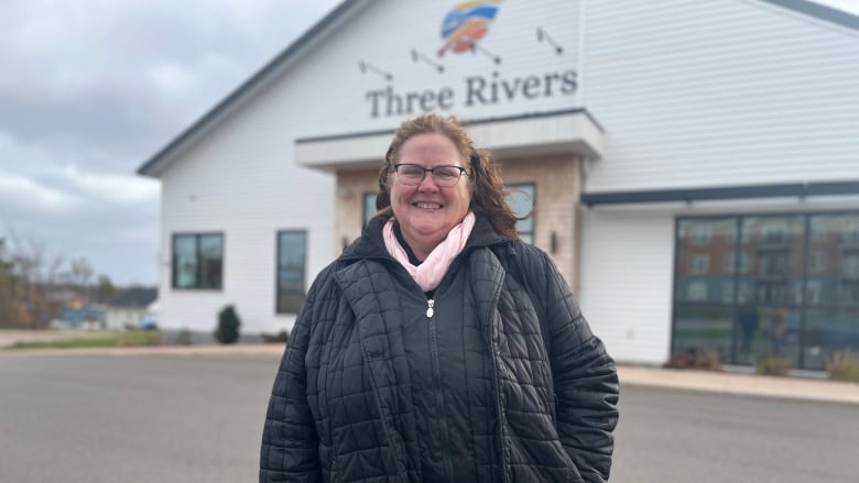 Woman in puffy jacket standing outside Three Rivers town hall.