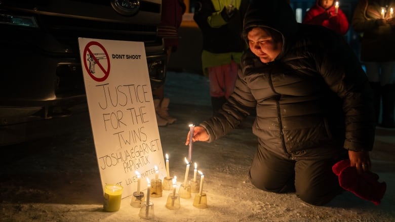 Person places candle by sign that reads 