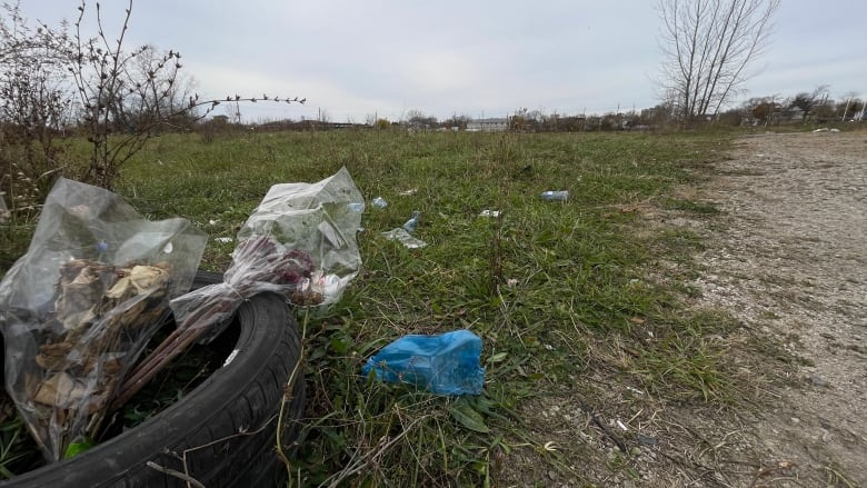 An empty lot with some trash on the grassy area.