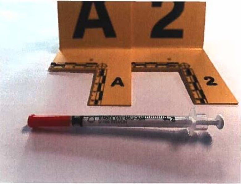 A syringe with an evidence marker in front of it.