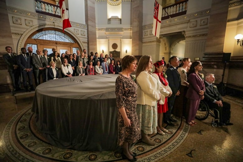 A number of people pose in a Legislature rotunda for a photo.