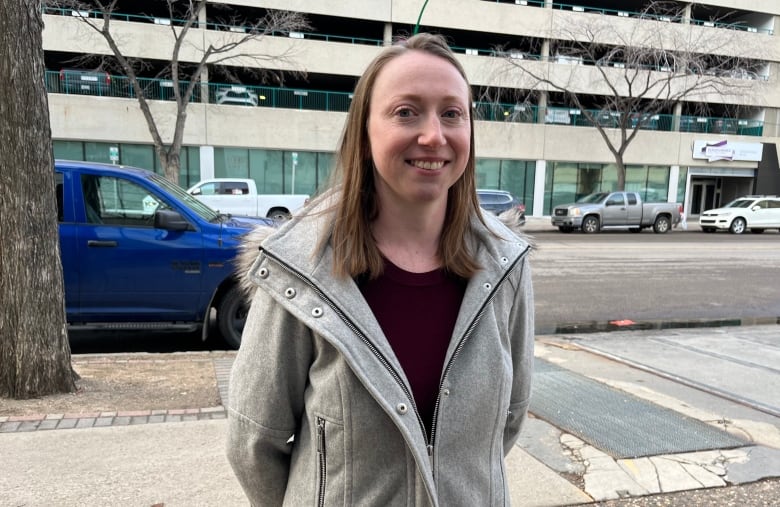 A woman stands outside on the sidewalk.