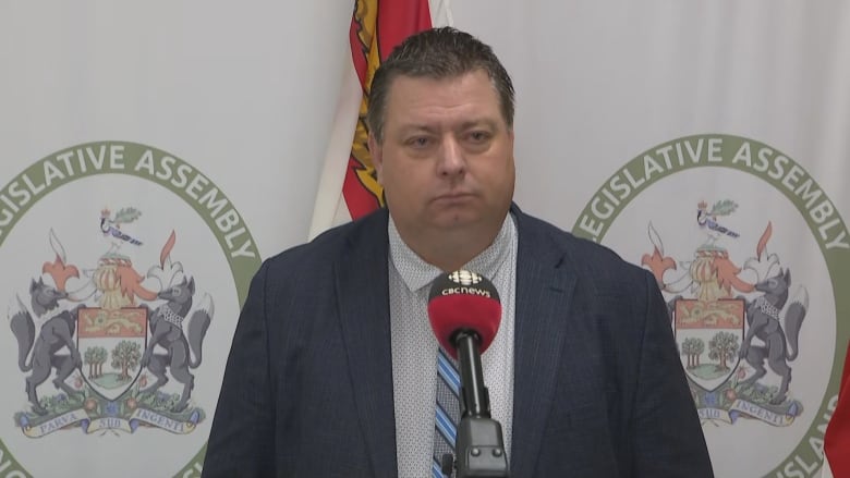 Man stands in front of Prince Edward Island flags.