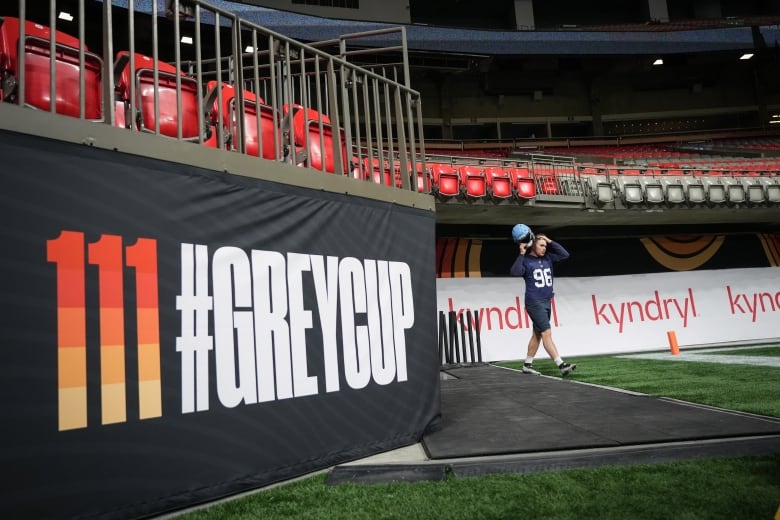 A football player walks into a stadium, next to a banner reading '111 #GreyCup.'