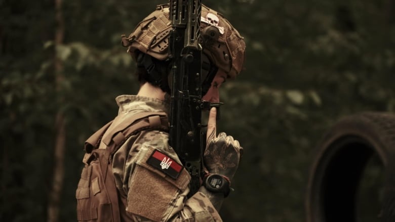 A woman in a military uniform holding an assault rifle.