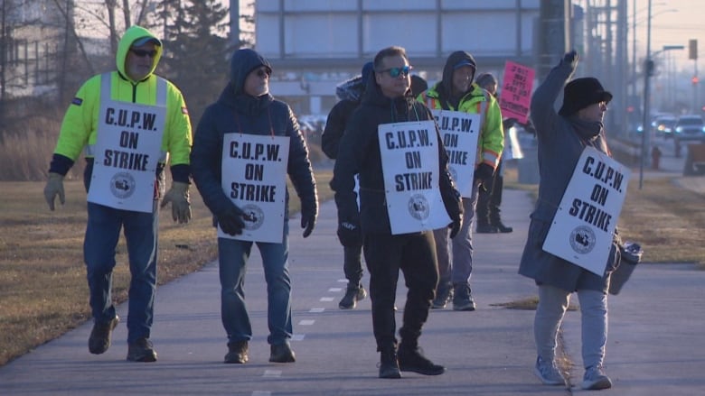 A group of people walk outside, wearing signs that say 